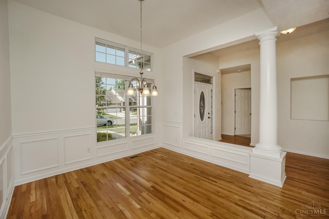 688 Humock Ct, Hamilton Twp, OH 45039 - unfurnished dining area featuring ornate columns, wood finished floors, a decorative wall, and a wainscoted wall