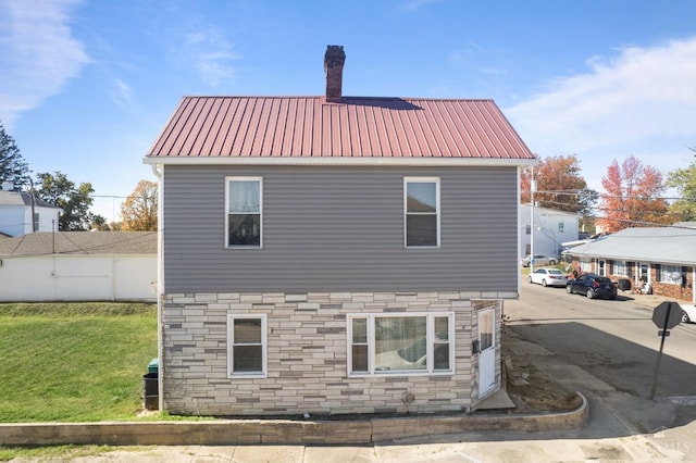 201 W Cherry St, Georgetown, OH 45121 - view of side of property featuring stone siding, a chimney, a yard, and a metal roof