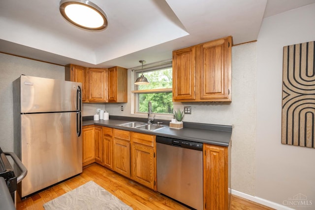 8385 Bridle Rd, Anderson Twp, OH 45244 - kitchen with stainless steel appliances, dark countertops, light wood-style floors, a tray ceiling, and brown cabinets