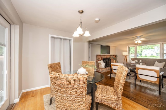 8385 Bridle Rd, Anderson Twp, OH 45244 - dining space with a brick fireplace, light wood-style flooring, and a chandelier