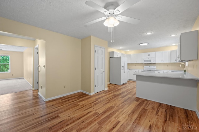 125 Sackett Dr, Monroe, OH 45050 - kitchen featuring white appliances, a peninsula, light wood-style flooring, a textured ceiling, and a ceiling fan