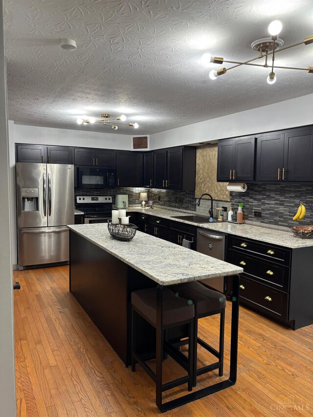 742 Miami Way Dr, Hamilton, OH 45013 - kitchen featuring stainless steel appliances, dark cabinetry, a center island, and a breakfast bar