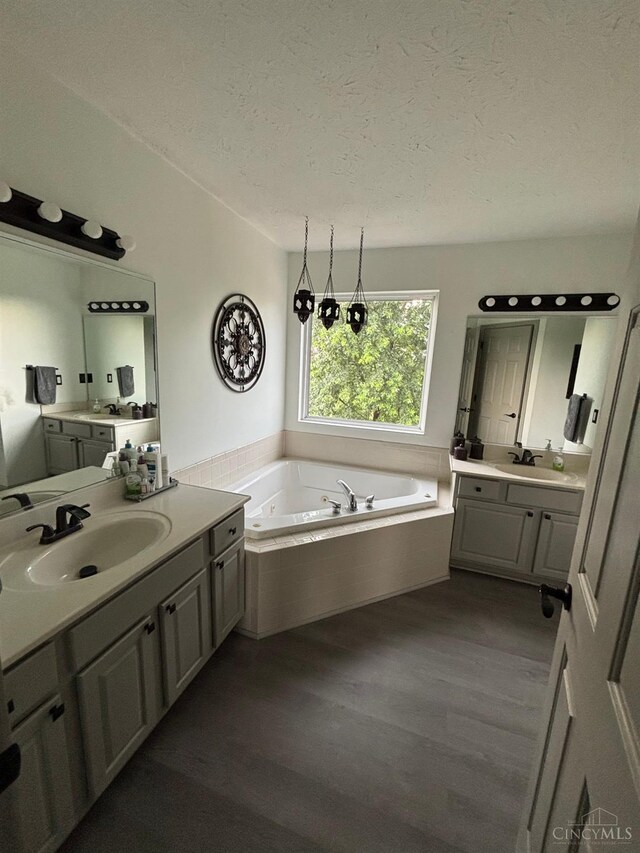 742 Miami Way Dr, Hamilton, OH 45013 - bathroom featuring a textured ceiling, wood finished floors, a bath, and two vanities