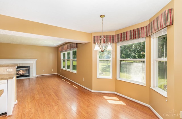 7693 Misty Springs Ct, Deerfield Twp, OH 45040 - unfurnished dining area with light wood-style floors, a chandelier, and a fireplace
