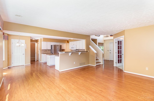 7693 Misty Springs Ct, Deerfield Twp, OH 45040 - unfurnished living room with light wood finished floors, stairway, and a chandelier