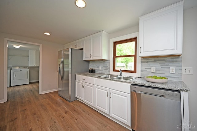 5782 Buckwheat Rd, Miami Twp, OH 45150 - kitchen featuring stainless steel appliances, washer and dryer, white cabinetry, tasteful backsplash, and wood finished floors