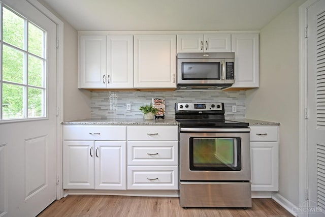 5782 Buckwheat Rd, Miami Twp, OH 45150 - kitchen featuring appliances with stainless steel finishes, decorative backsplash, light wood-style flooring, and white cabinetry
