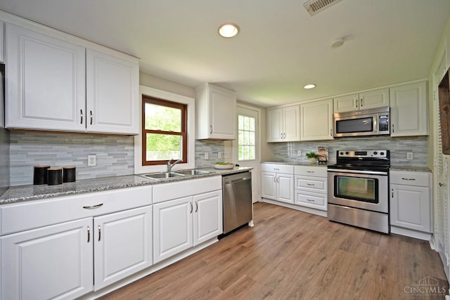 5782 Buckwheat Rd, Miami Twp, OH 45150 - kitchen with appliances with stainless steel finishes, white cabinetry, decorative backsplash, light wood-style floors, and recessed lighting