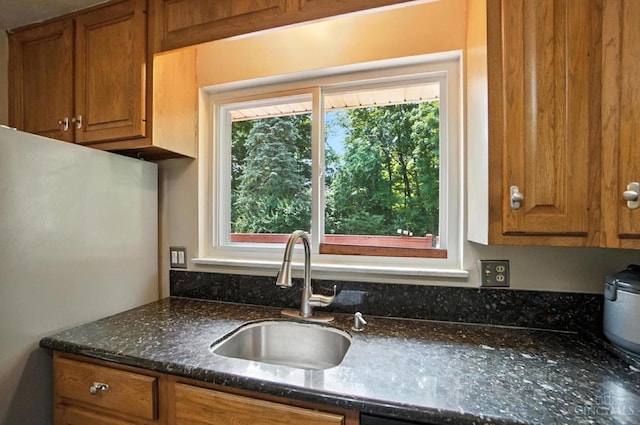 9015 Cotillion Dr, Springfield Twp, OH 45231 - kitchen with freestanding refrigerator, brown cabinetry, and dark stone countertops