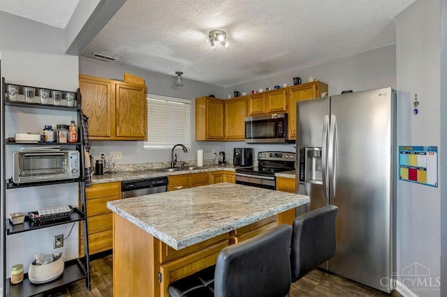 6706 Bedington Ln, Morrow, OH 45152 - kitchen with appliances with stainless steel finishes, a textured ceiling, light countertops, dark wood-style flooring, and a kitchen island