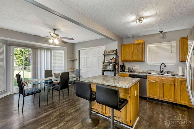 6706 Bedington Ln, Morrow, OH 45152 - kitchen featuring appliances with stainless steel finishes, a textured ceiling, dark wood-style flooring, a kitchen island, and a breakfast bar
