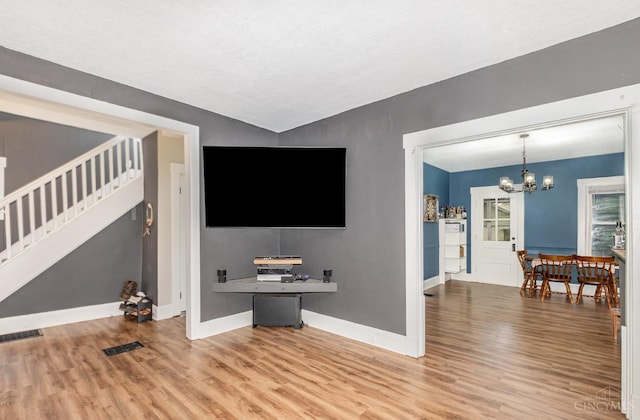 609 Coralie Ave, Hamilton, OH 45013 - unfurnished living room featuring stairs, wood finished floors, and a chandelier