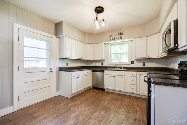 732 Central Ave, Carlisle, OH 45005 - kitchen with stainless steel appliances, dark wood-type flooring, white cabinetry, dark countertops, and hanging light fixtures