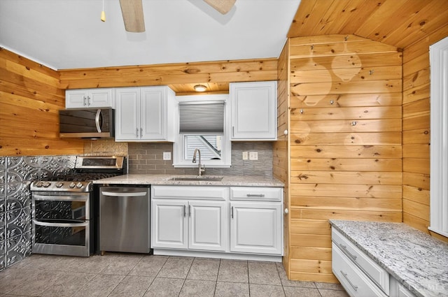 4644 Alpine Ave, Blue Ash, OH 45242 - kitchen with stainless steel appliances, vaulted ceiling, tasteful backsplash, white cabinetry, and wood walls