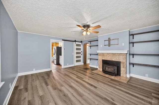 4644 Alpine Ave, Blue Ash, OH 45242 - unfurnished living room with ceiling fan, a wood stove, wood finished floors, crown molding, and a textured ceiling