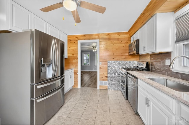 4644 Alpine Ave, Blue Ash, OH 45242 - kitchen with stainless steel appliances, ceiling fan, white cabinets, decorative backsplash, and wood walls