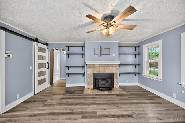 4644 Alpine Ave, Blue Ash, OH 45242 - unfurnished living room with a wood stove, wood finished floors, a textured ceiling, ceiling fan, and arched walkways
