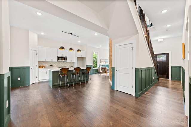 2241 Kemper Ln, Cincinnati, OH 45206 - kitchen featuring stainless steel microwave, green cabinets, white cabinetry, a wainscoted wall, and light countertops