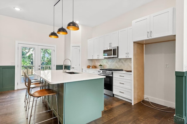 2241 Kemper Ln, Cincinnati, OH 45206 - kitchen featuring appliances with stainless steel finishes, dark wood-style floors, an island with sink, white cabinetry, and recessed lighting