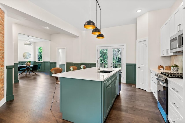 2241 Kemper Ln, Cincinnati, OH 45206 - kitchen featuring stainless steel appliances, green cabinetry, wainscoting, dark wood-style floors, and white cabinets