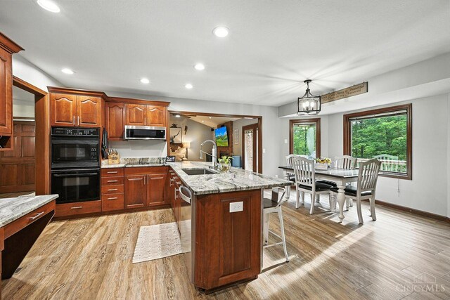 11545 Deer Trace Ln, Harrison Twp, OH 45030 - kitchen featuring black appliances, a kitchen breakfast bar, light wood finished floors, a peninsula, and light stone counters