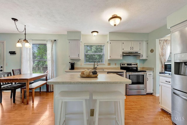 1165 Mcguffey Ln, Union Twp, OH 45103 - kitchen featuring stainless steel appliances, under cabinet range hood, light wood-type flooring, healthy amount of natural light, and a textured ceiling