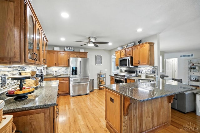 1751 Tatum Ln, Hamilton, OH 45013 - kitchen with stainless steel appliances, a peninsula, ceiling fan, decorative backsplash, and brown cabinetry