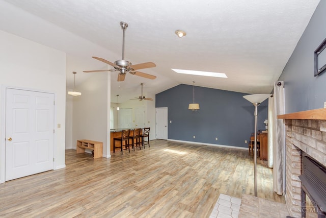 207 Valhalla Cv, Lakengren, OH 45320 - living area featuring a ceiling fan, vaulted ceiling, light wood-style flooring, a fireplace, and a skylight