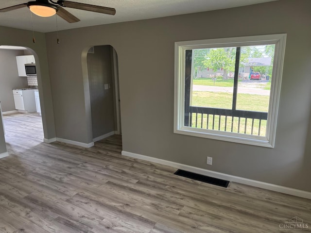 569 Beissinger Rd, Saint Clair Twp, OH 45013 - spare room with arched walkways, a ceiling fan, and wood finished floors