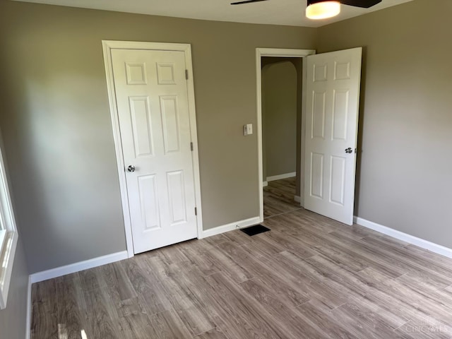 569 Beissinger Rd, Saint Clair Twp, OH 45013 - unfurnished bedroom featuring wood finished floors, arched walkways, and ceiling fan
