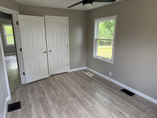 569 Beissinger Rd, Saint Clair Twp, OH 45013 - unfurnished bedroom featuring multiple windows, light wood-type flooring, and a closet