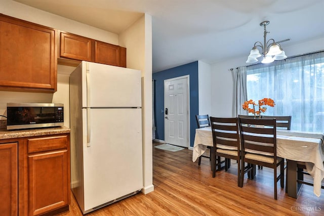 2465 Wilson Ave, Cincinnati, OH 45231 - kitchen with freestanding refrigerator, stainless steel microwave, a chandelier, and brown cabinets