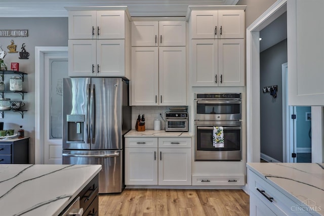7948 Red Fox Trl, Hamilton Twp, OH 45152 - kitchen featuring appliances with stainless steel finishes, white cabinetry, decorative backsplash, light stone countertops, and light wood-style flooring