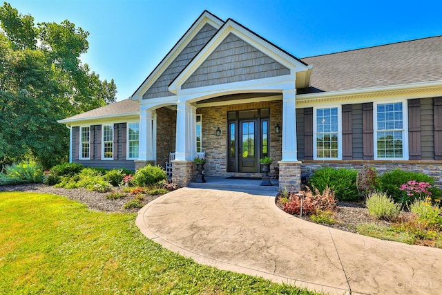 7948 Red Fox Trl, Hamilton Twp, OH 45152 - view of exterior entry with a yard, stone siding, roof with shingles, and a porch
