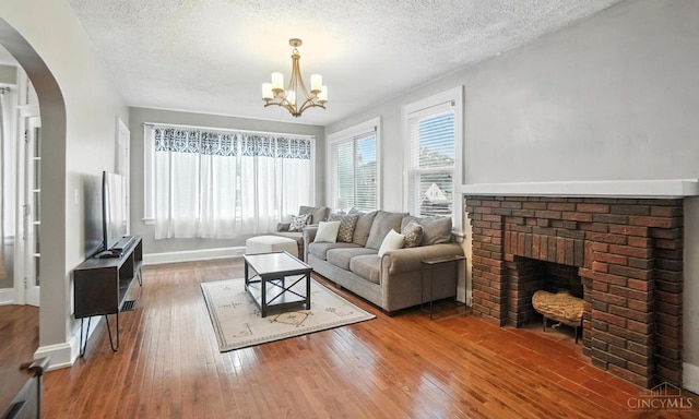 3462 Wabash Ave, Cincinnati, OH 45207 - living room with a fireplace, arched walkways, hardwood / wood-style floors, a chandelier, and a textured ceiling