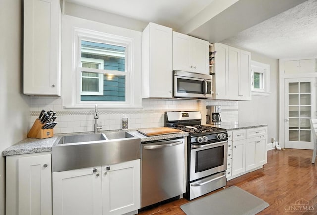 3462 Wabash Ave, Cincinnati, OH 45207 - kitchen with stainless steel appliances, decorative backsplash, dark wood-style flooring, white cabinetry, and a textured ceiling