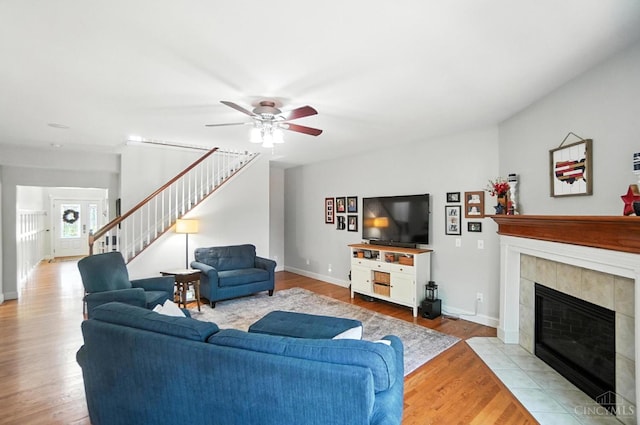 8608 Sunmont Dr, Anderson Twp, OH 45255 - living area with stairs, ceiling fan, a tile fireplace, and wood finished floors