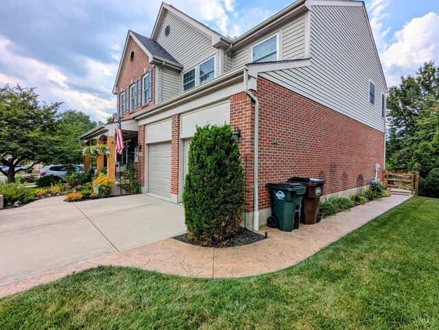 8608 Sunmont Dr, Anderson Twp, OH 45255 - view of side of home with concrete driveway, brick siding, an attached garage, and a yard