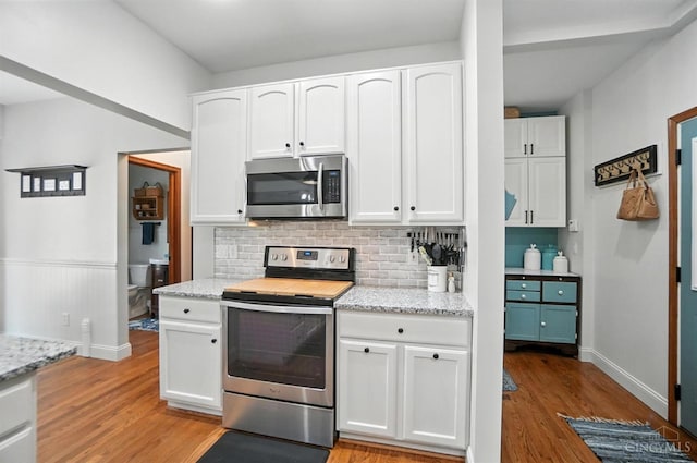 8608 Sunmont Dr, Anderson Twp, OH 45255 - kitchen with appliances with stainless steel finishes, light wood-style flooring, backsplash, white cabinetry, and light stone countertops