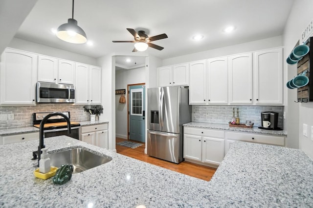 8608 Sunmont Dr, Anderson Twp, OH 45255 - kitchen with appliances with stainless steel finishes, tasteful backsplash, a ceiling fan, light wood-style floors, and white cabinets