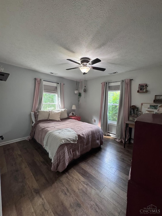 9063 Morrow Woodville Rd, Harlan Twp, OH 45162 - bedroom with multiple windows, dark wood-type flooring, a textured ceiling, and a ceiling fan