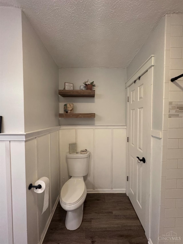 9063 Morrow Woodville Rd, Harlan Twp, OH 45162 - bathroom featuring wood finished floors, a textured ceiling, a decorative wall, and a wainscoted wall