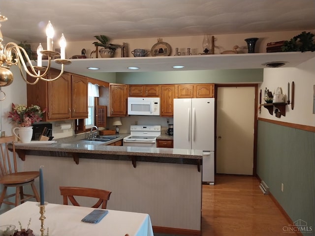 13353 State Route 28 W, Greenfield, OH 45123 - kitchen featuring white appliances, a chandelier, brown cabinetry, a peninsula, and light wood-style floors
