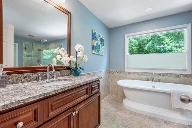 8551 Trillium Ridge Ln, Anderson Twp, OH 45255 - bathroom featuring a shower stall, a freestanding tub, vanity, tile patterned floors, and tile walls