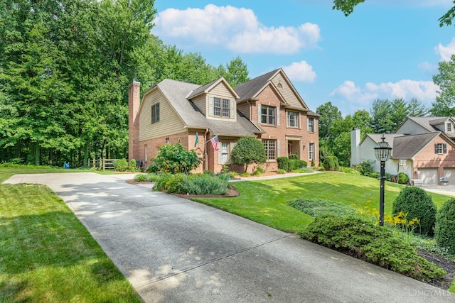 8551 Trillium Ridge Ln, Anderson Twp, OH 45255 - view of front of house with brick siding, a chimney, a front lawn, and concrete driveway
