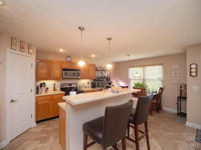 7854 Cape Cod Ct, West Chester, OH 45069 - kitchen featuring appliances with stainless steel finishes, light countertops, a kitchen bar, a center island, and pendant lighting
