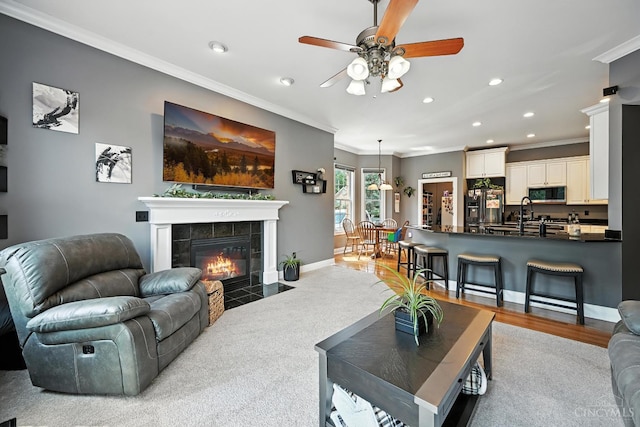 7066 Hearthside Ct, Liberty Twp, OH 45011 - living room featuring crown molding, recessed lighting, a ceiling fan, a tiled fireplace, and wood finished floors