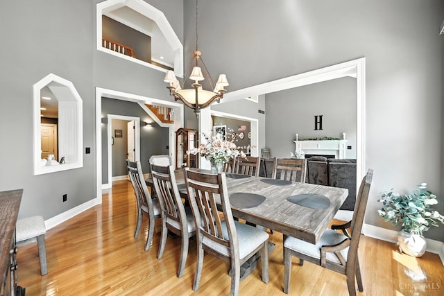7066 Hearthside Ct, Liberty Twp, OH 45011 - dining room with a high ceiling, light wood-type flooring, a fireplace, and a chandelier