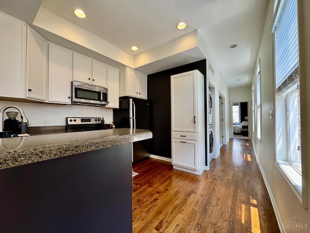 955 Pavilion St Unit 4, Cincinnati, OH 45202 - kitchen featuring appliances with stainless steel finishes, stacked washer / dryer, white cabinetry, dark wood-type flooring, and recessed lighting
