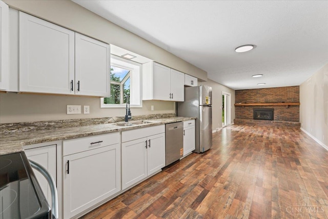 2535 Crane Schoolhouse Rd, Tate Twp, OH 45106 - kitchen featuring appliances with stainless steel finishes, white cabinetry, dark wood finished floors, a brick fireplace, and light stone counters